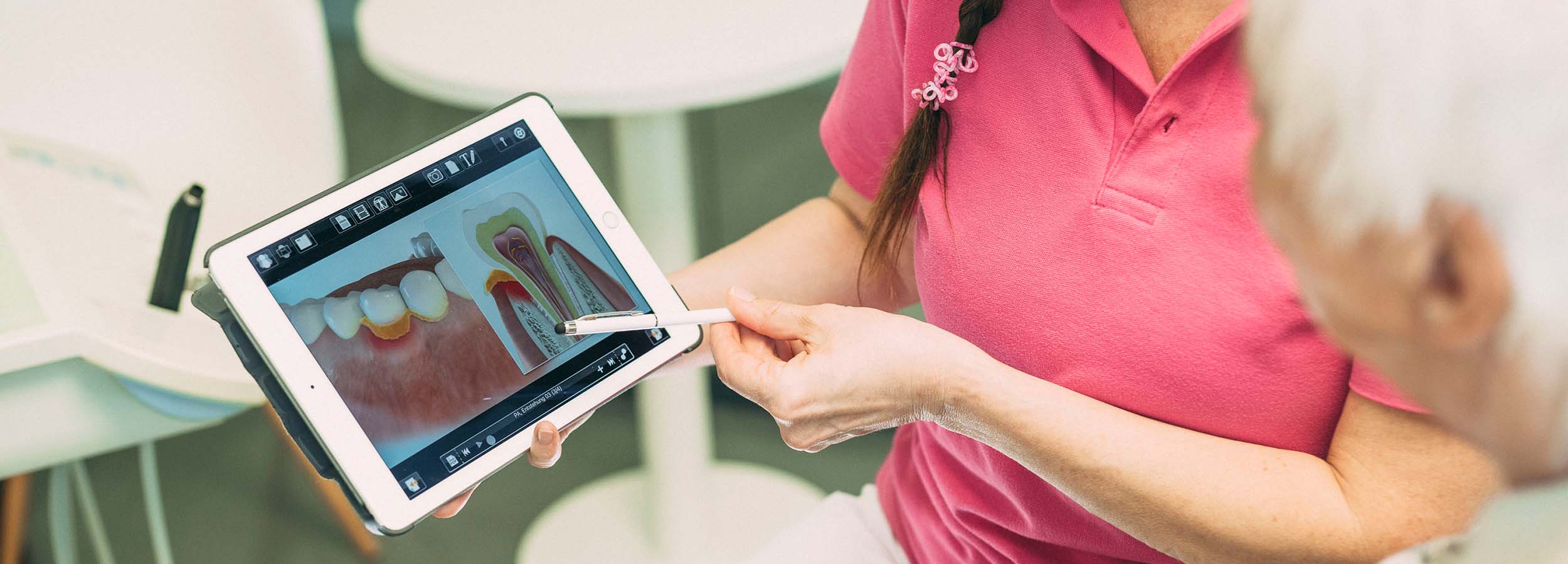 Detailaufnahme eines Tablets in der Hand einer Ärztin: Auf dem Bildschirm wird das Röntgen-Bild eines Parodontitis-Patienten gezeigt.